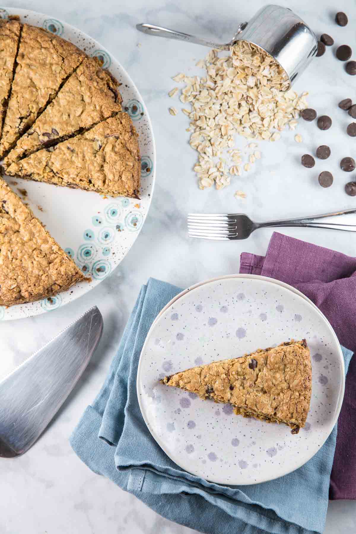 giant oatmeal chocolate chip cookie cut into wedges with one slice on a dessert plate