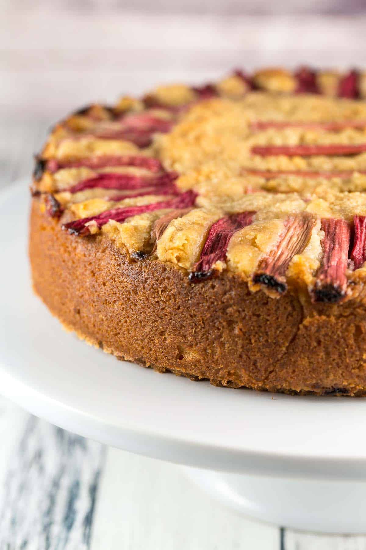 side view of a coffee cake topped with slices of sugar-soaked rhubarb