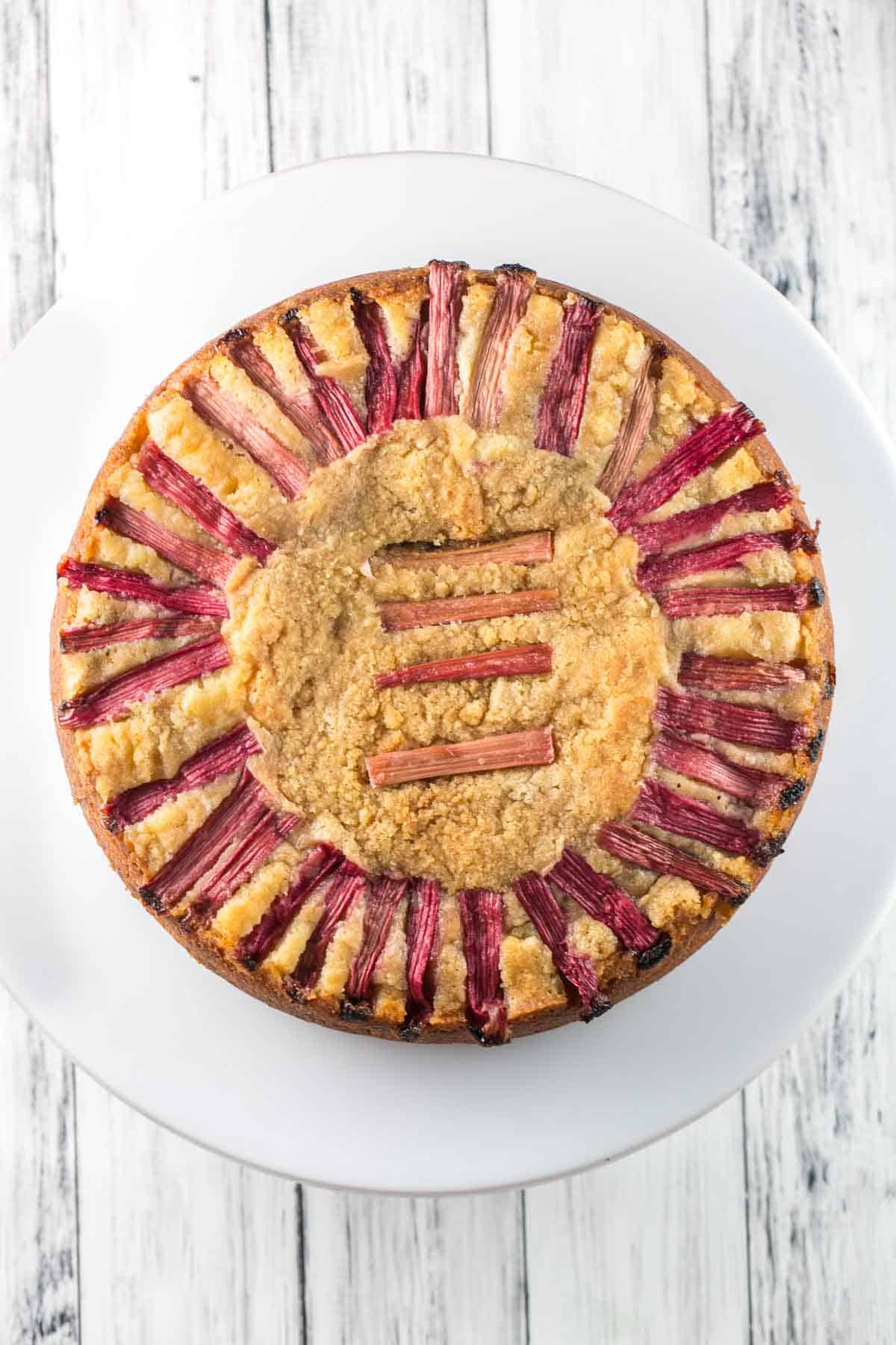 overhead view of a coffee cake topped with bright red stalks of rhubarb