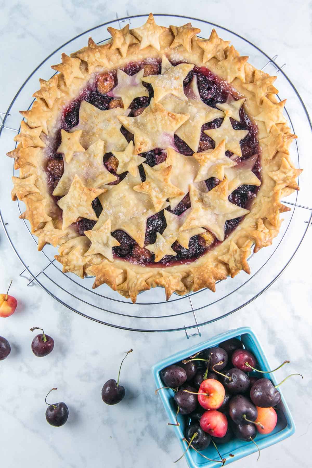 cherry pie on a cooling rack covered with star-shaped pie crust cutouts