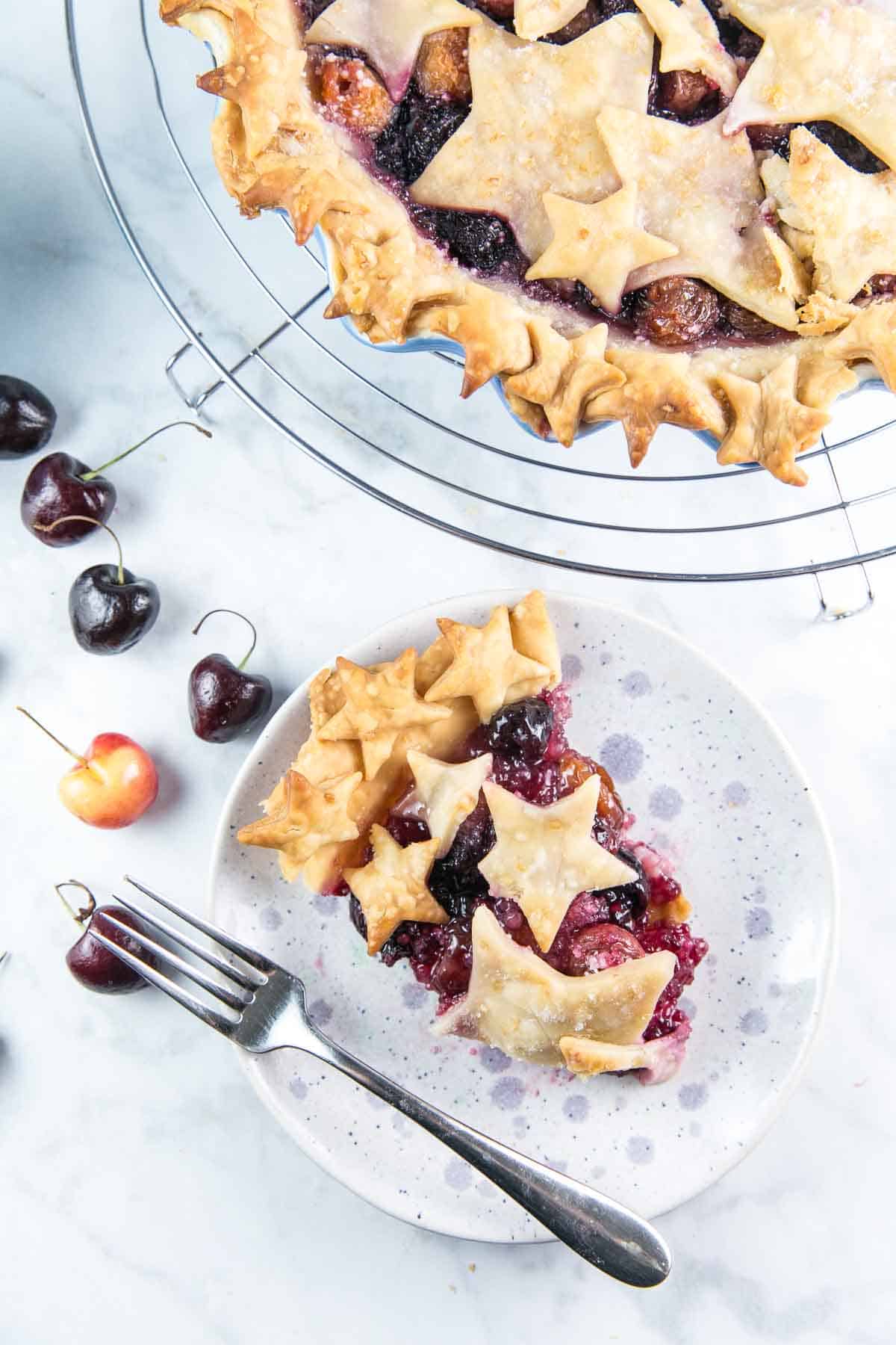 single slice of cherry pie covered in cutout crust stars on a small dessert plate