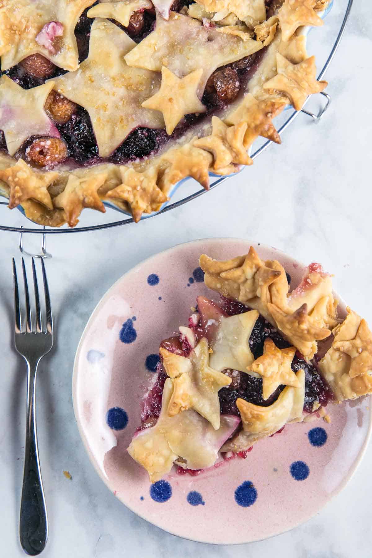 slice of homemade cherry almond pie on a pink and blue dessert plate