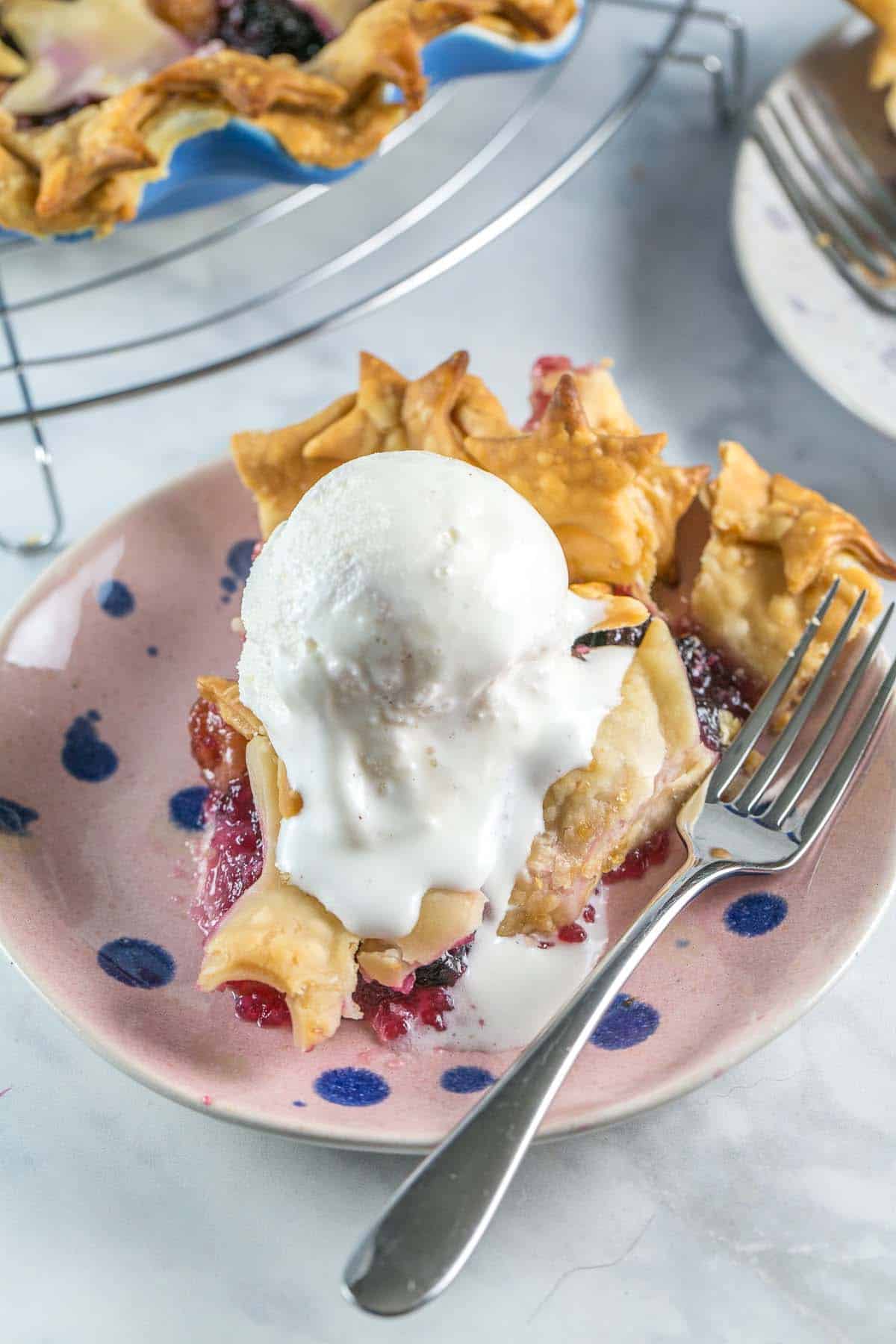 slice of cherry pie covered with a big scoop of vanilla ice cream