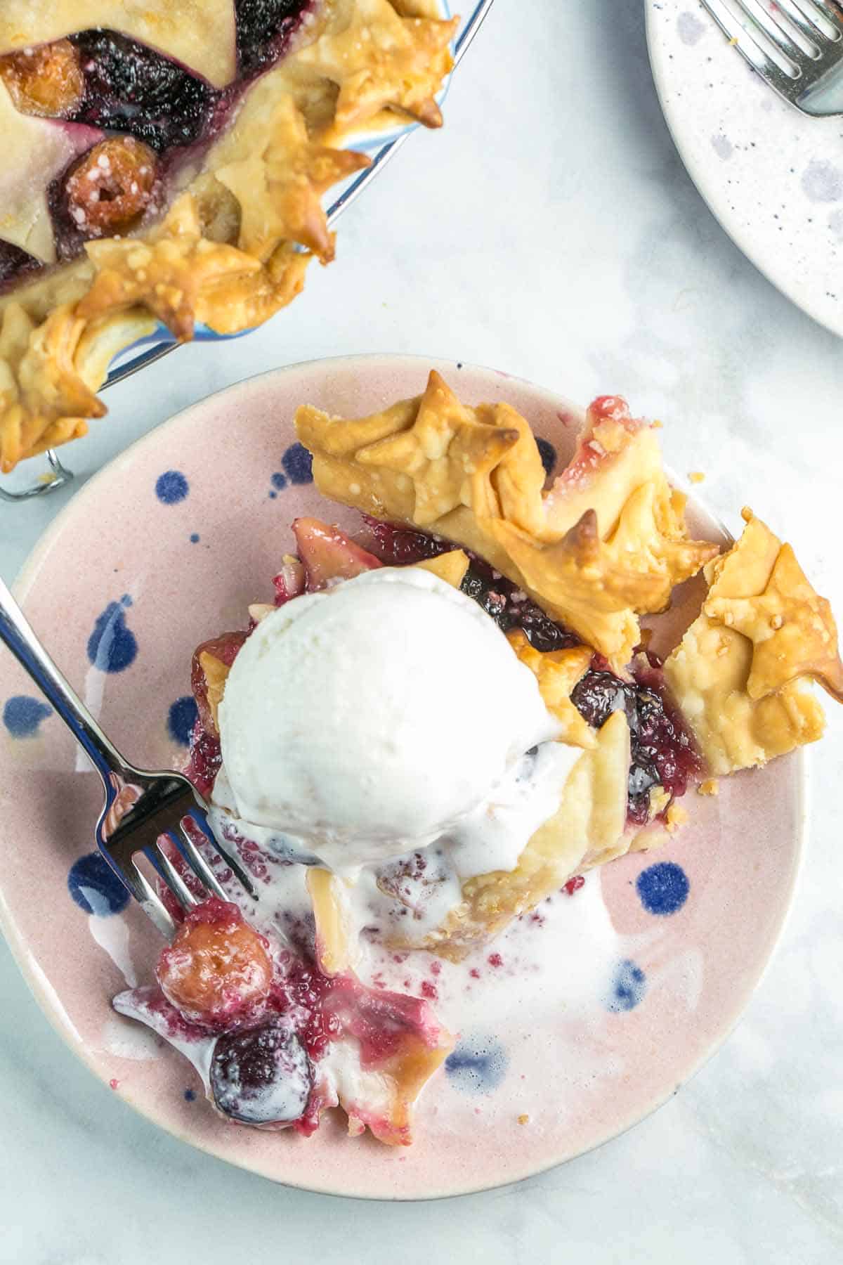 slice of pie on a plate with a melting scoop of ice cream mixing in with the cherry filling