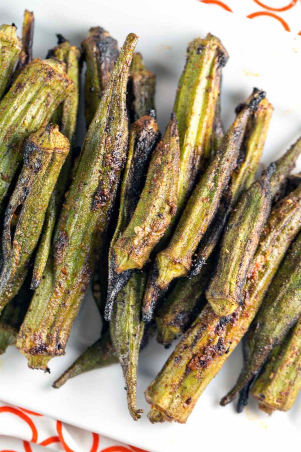 grilled okra covered in spices and stacked on a white serving dish