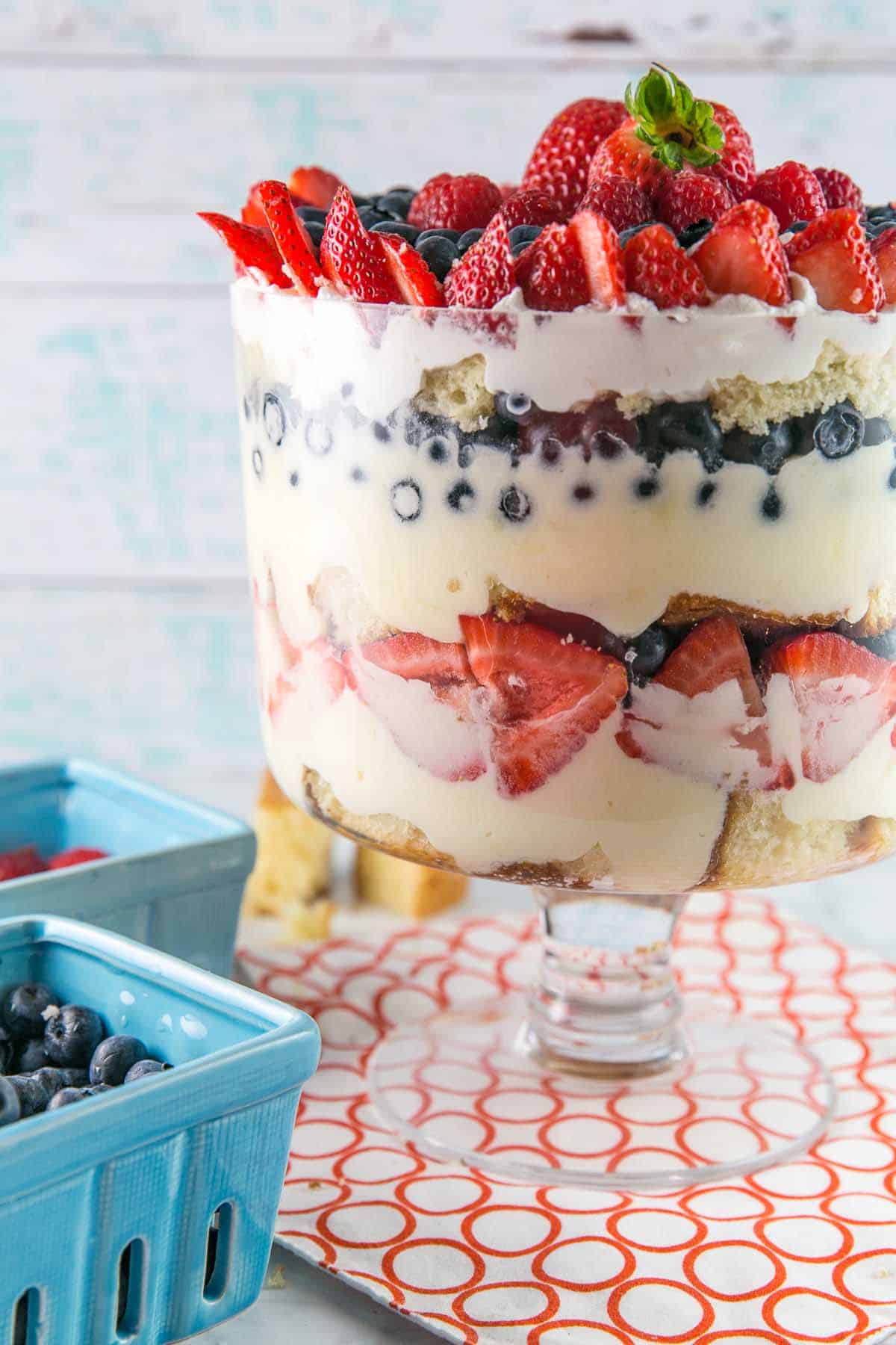 trifle bowl filled with layers of cake, homemade custard, and berries