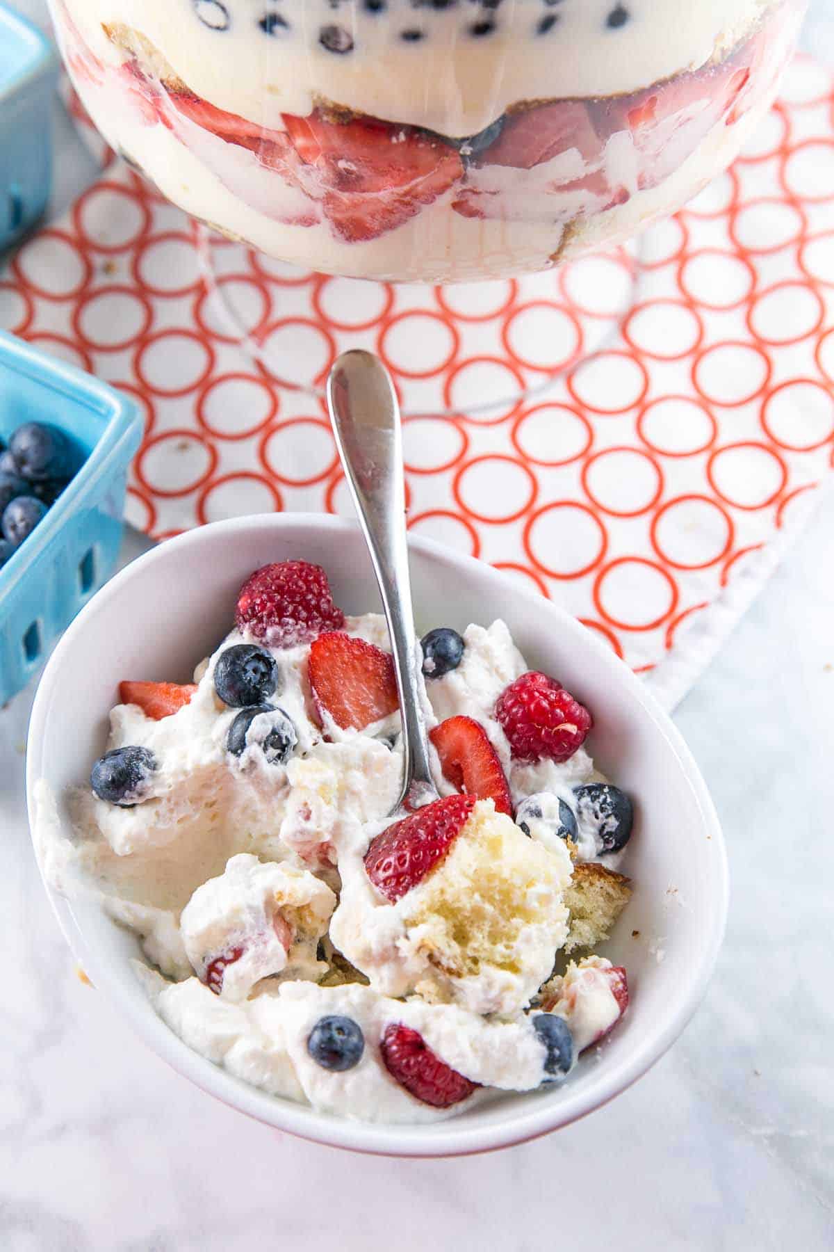 cake mixed with lemon custard and fresh berries in a white dessert bowl