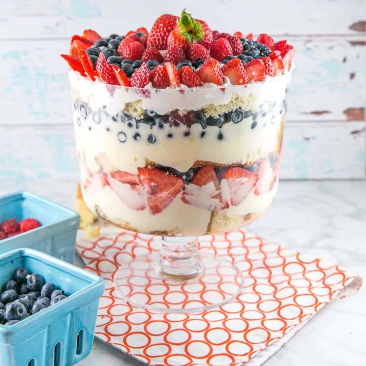 trifle bowl filled with layers of cake, lemon custard, and fresh summer berries