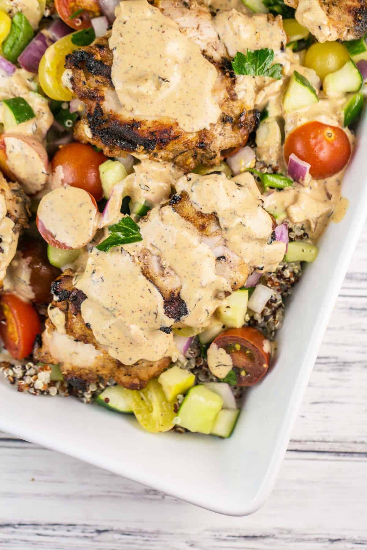 grilled chicken on a cucumber quinoa salad with tahini dressing