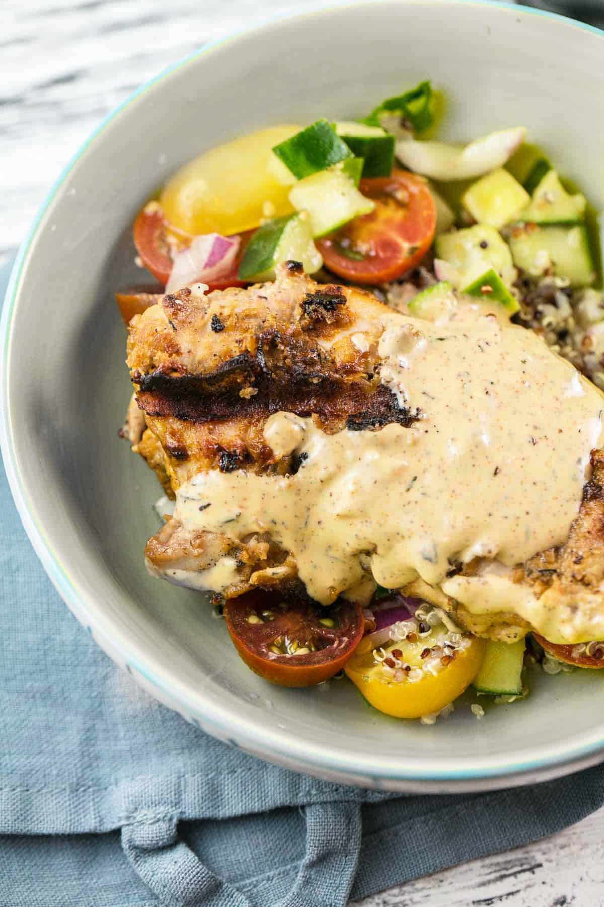 grilled chicken with tahini sauce and salad in a ceramic bowl