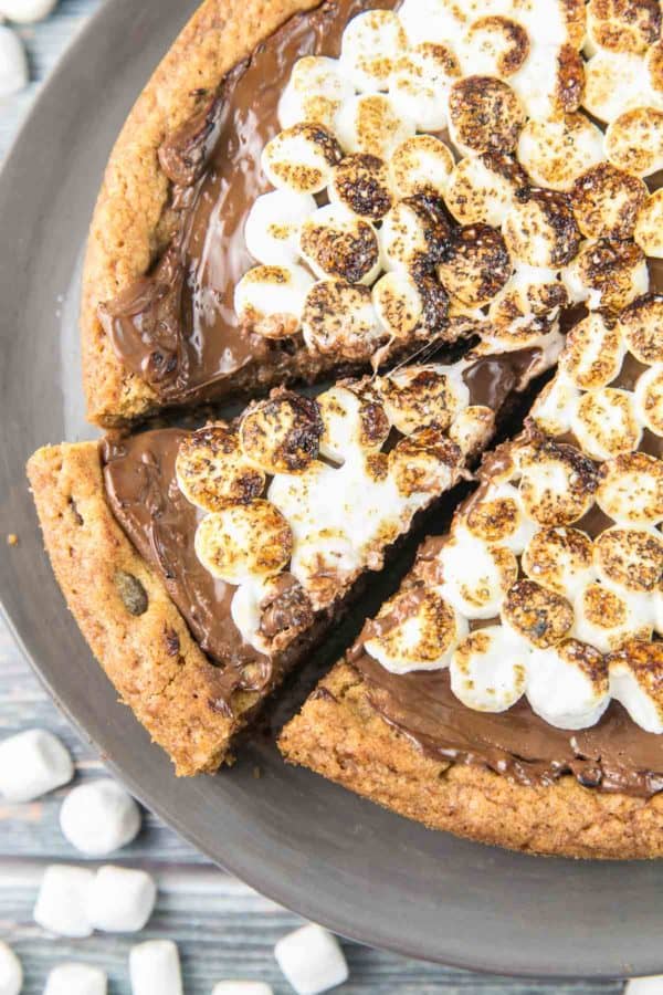S'mores Cookie Cake: a giant graham cracker chocolate chip cookie cake, covered with a layer of melted milk chocolate and toasted s'mores. A perfect nostalgic childhood treat! {Bunsen Burner Bakery} #smores #cookiecake #giantcookie #smorescookiecake