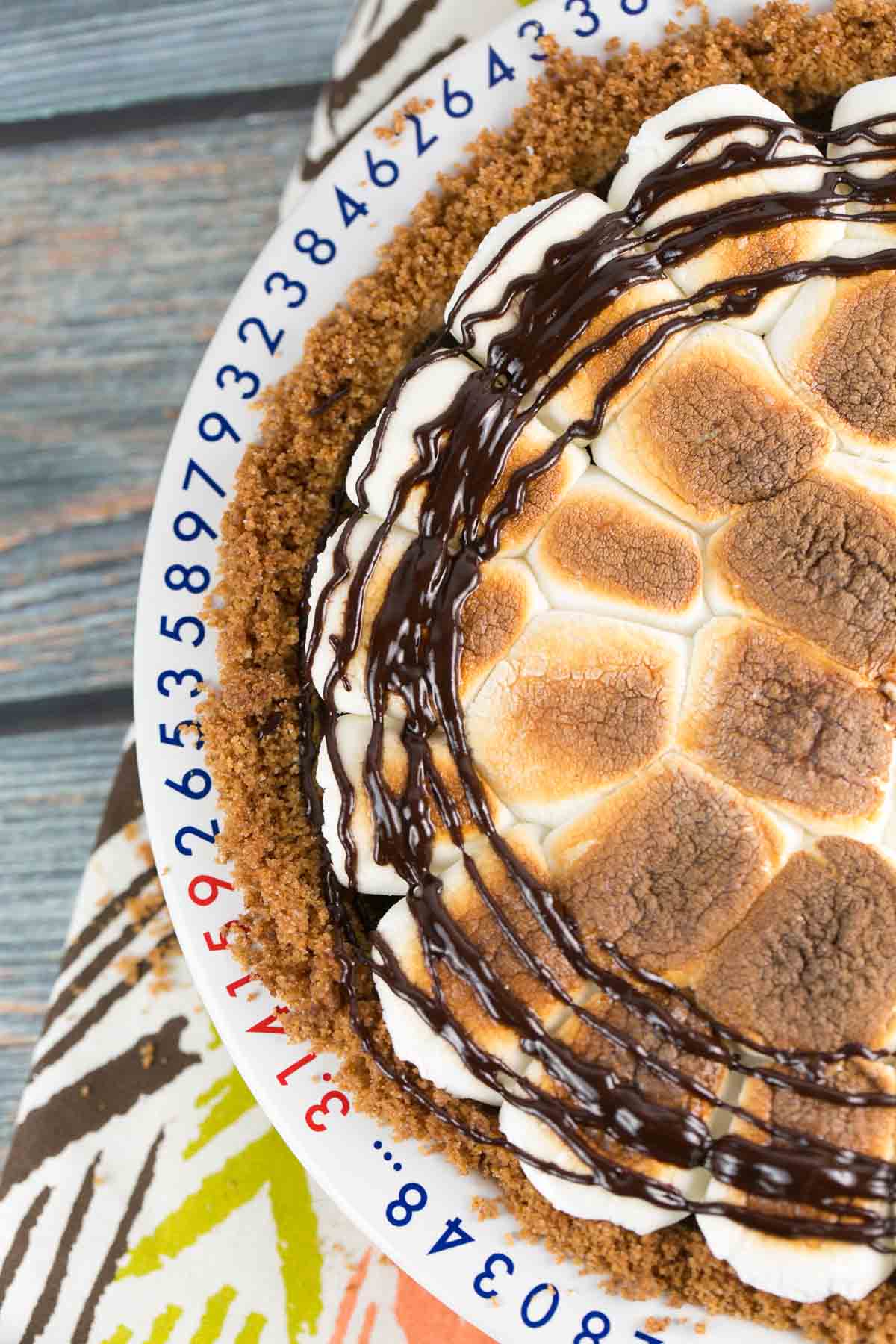 overhead view of s'mores pie with toasted marshmallows on top and a chocolate drizzle