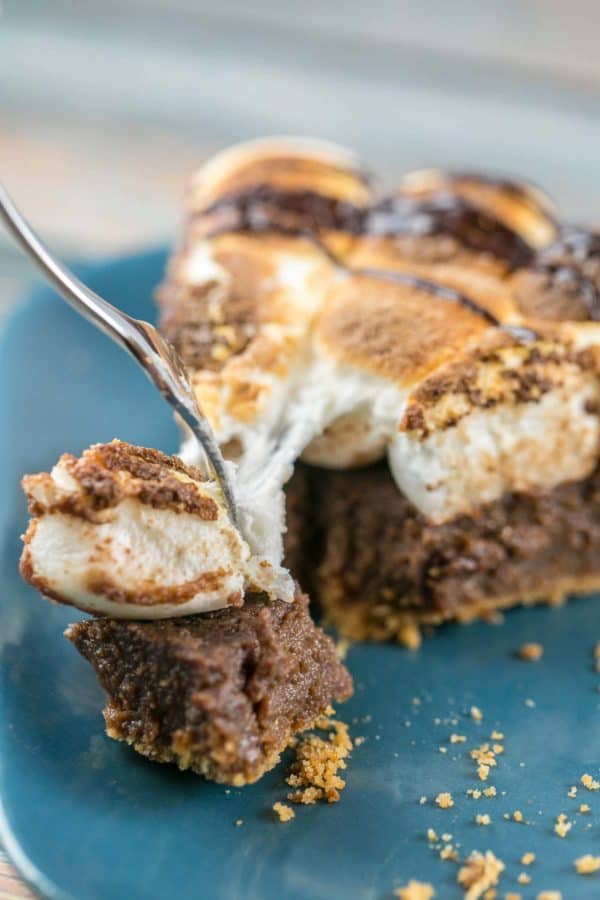 a fork pulling away a bite of s'mores pie with long gooey toasted marshmallow strings
