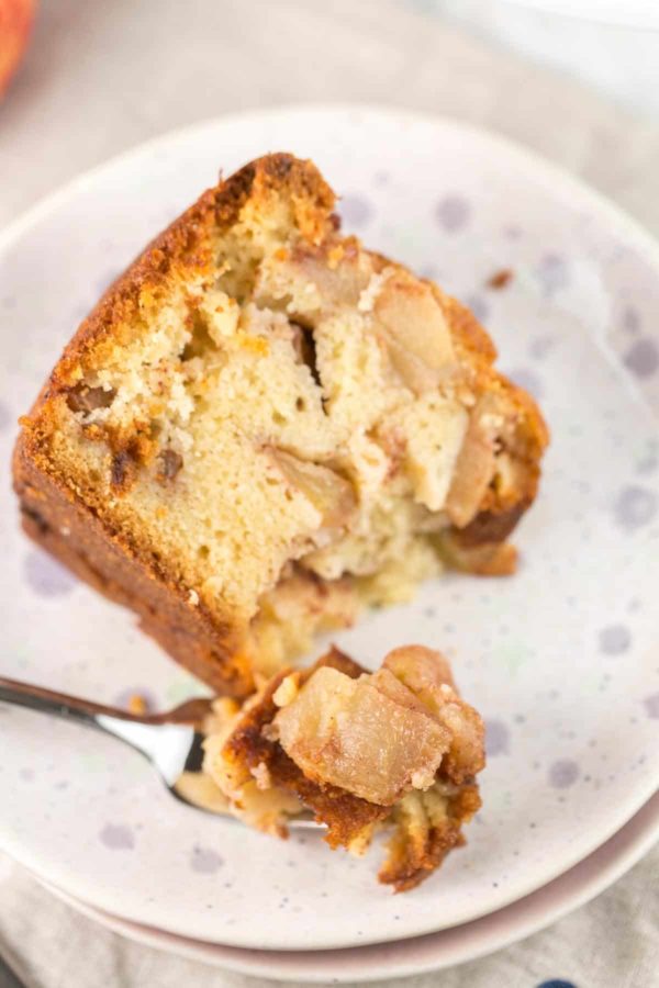 a slice of easy homemade apple cake made with orange juice and fresh apples with one forkful removed and the fork resting on the plate
