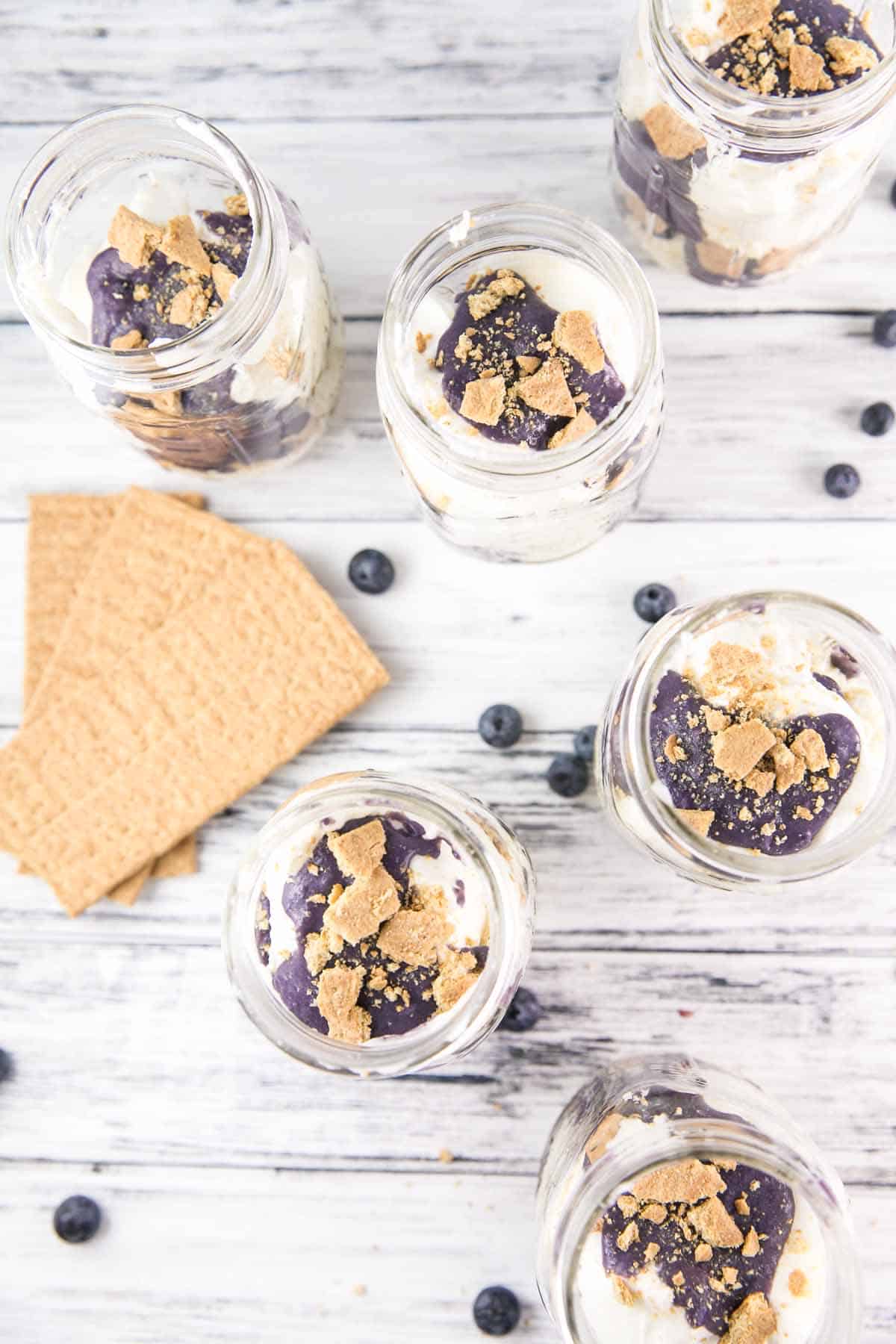 top view of cheesecake-filled mason jars with graham crackers crumbled on top