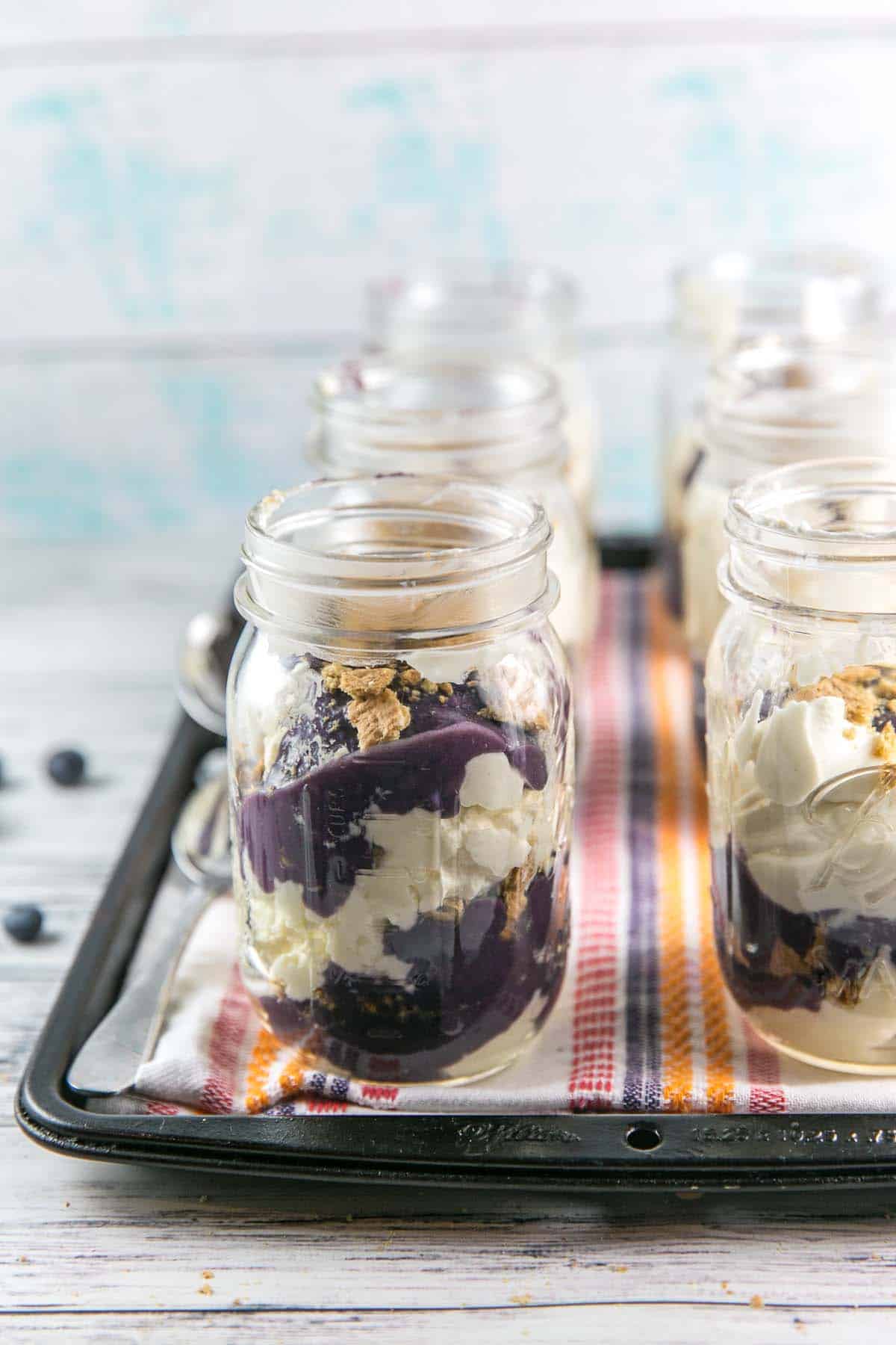 No Bake Cheesecake Parfaits with Blueberry Curd: an easy, fancy, make ahead treat perfect for dinner parties. Layers of a cream cheese and mascarpone cheesecake, blueberry cardamom curd, and crumbled graham crackers. #bunsenburnerbakery #cheesecake #cheesecakeparfaits #nobakedesserts