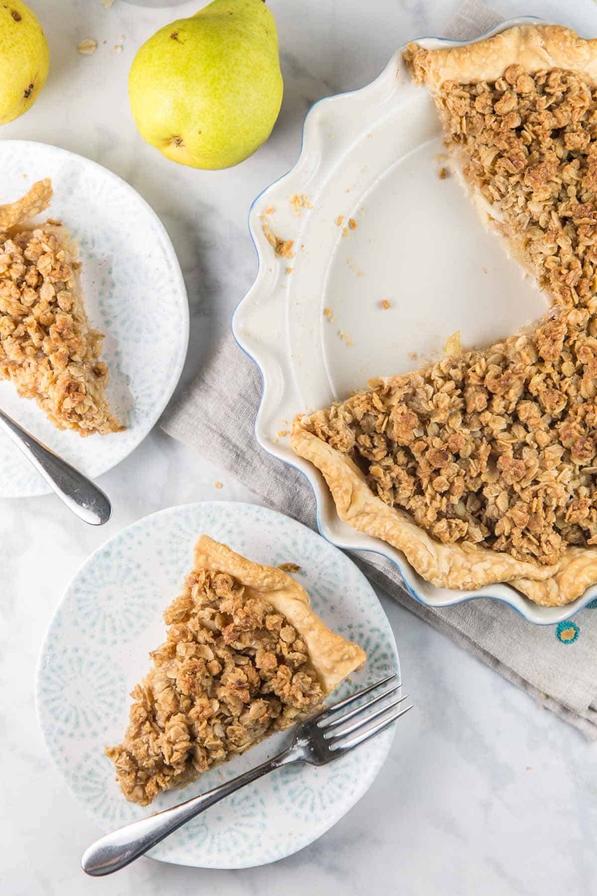 overhead view of a pear pie with two slices removed and served on white and blue plates.