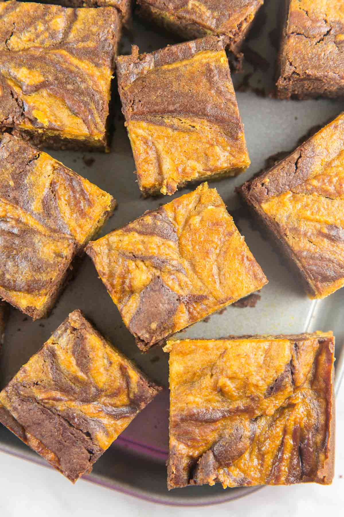 overhead view of orange and brown pumpkin swirl brownies on a metal dish.