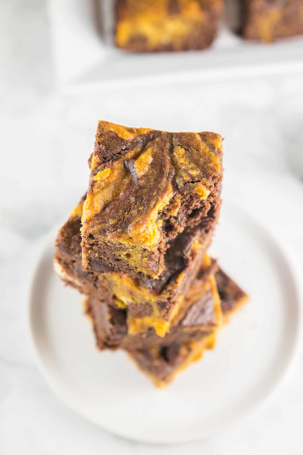 overhead view of a stack of pumpkin swirl brownies with one bite taken out of the top brownie.