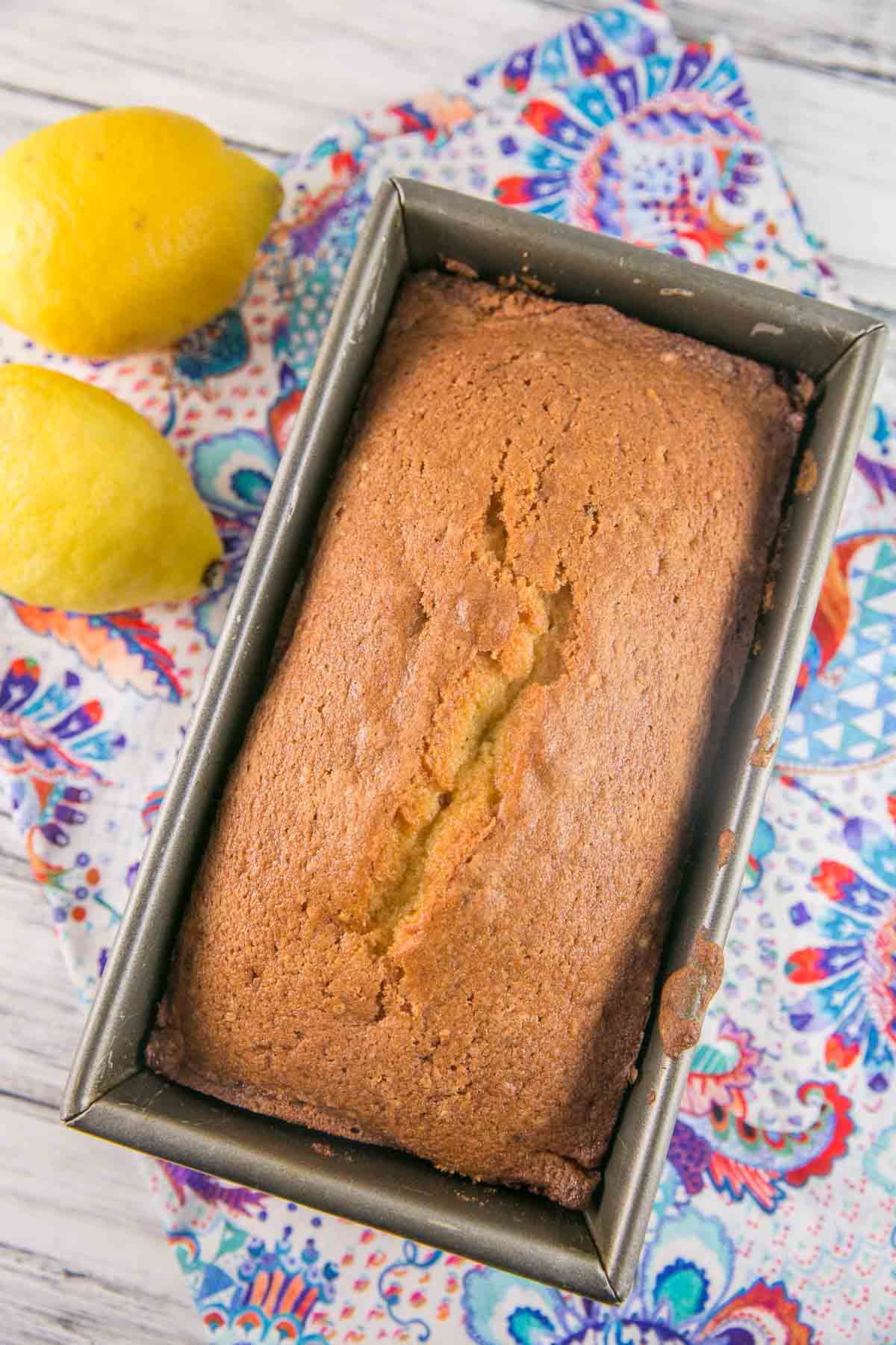 a lemon pound cake in a loaf pan on a paisley placemat