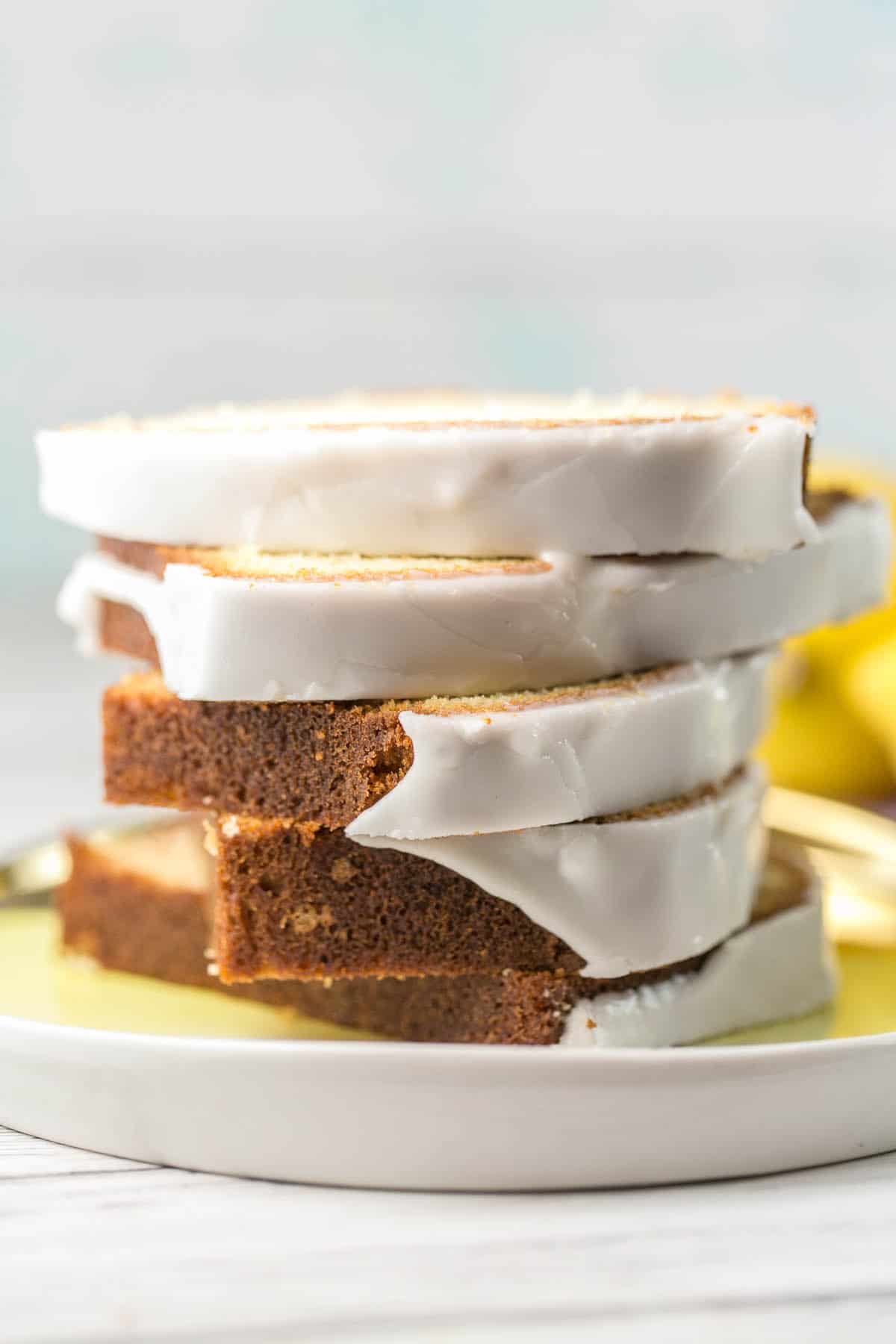 side view of five slices of glazed lemon pound cake stacked on a yellow plate