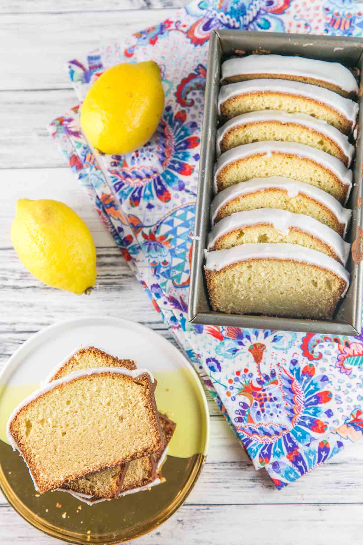slices of glazed lemon pound cake arranged on a yellow plate and in a loaf pan