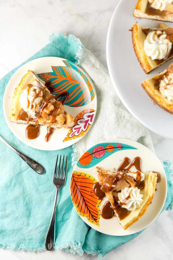 overhead view of two slices of caramel apple cheesecake on plates with leaf designs.