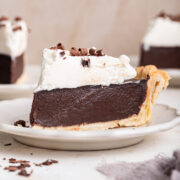 side view of a slice of chocolate cream pie covered in whipped cream.