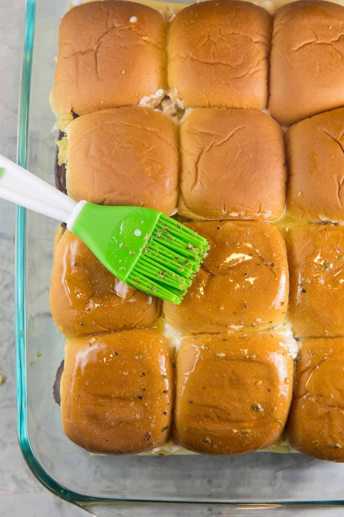 brushing slider rolls with melted butter and herbs