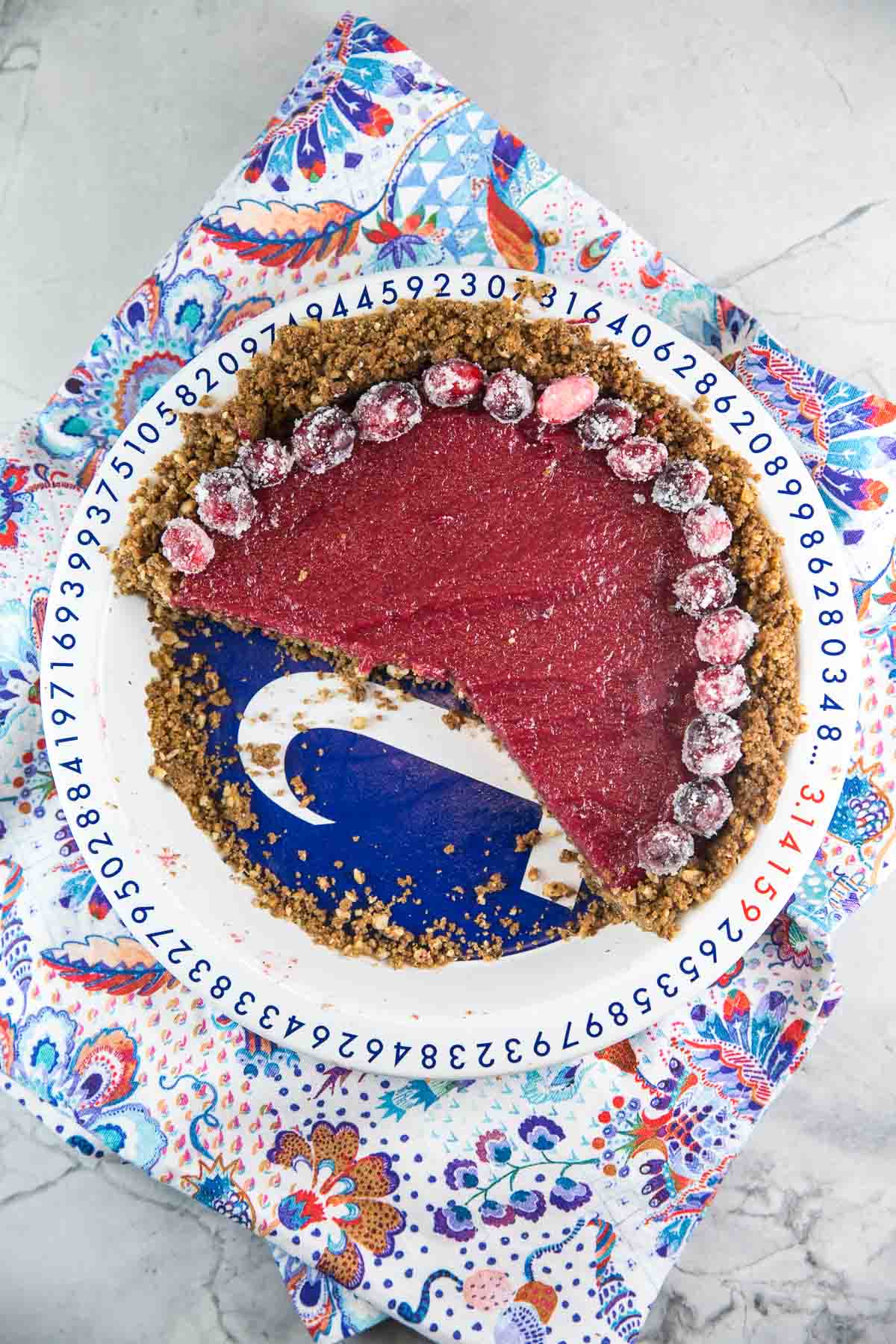 cranberry curd pie with a gingersnap crust in a pi-themed pi plate with a ring of sugared cranberries.