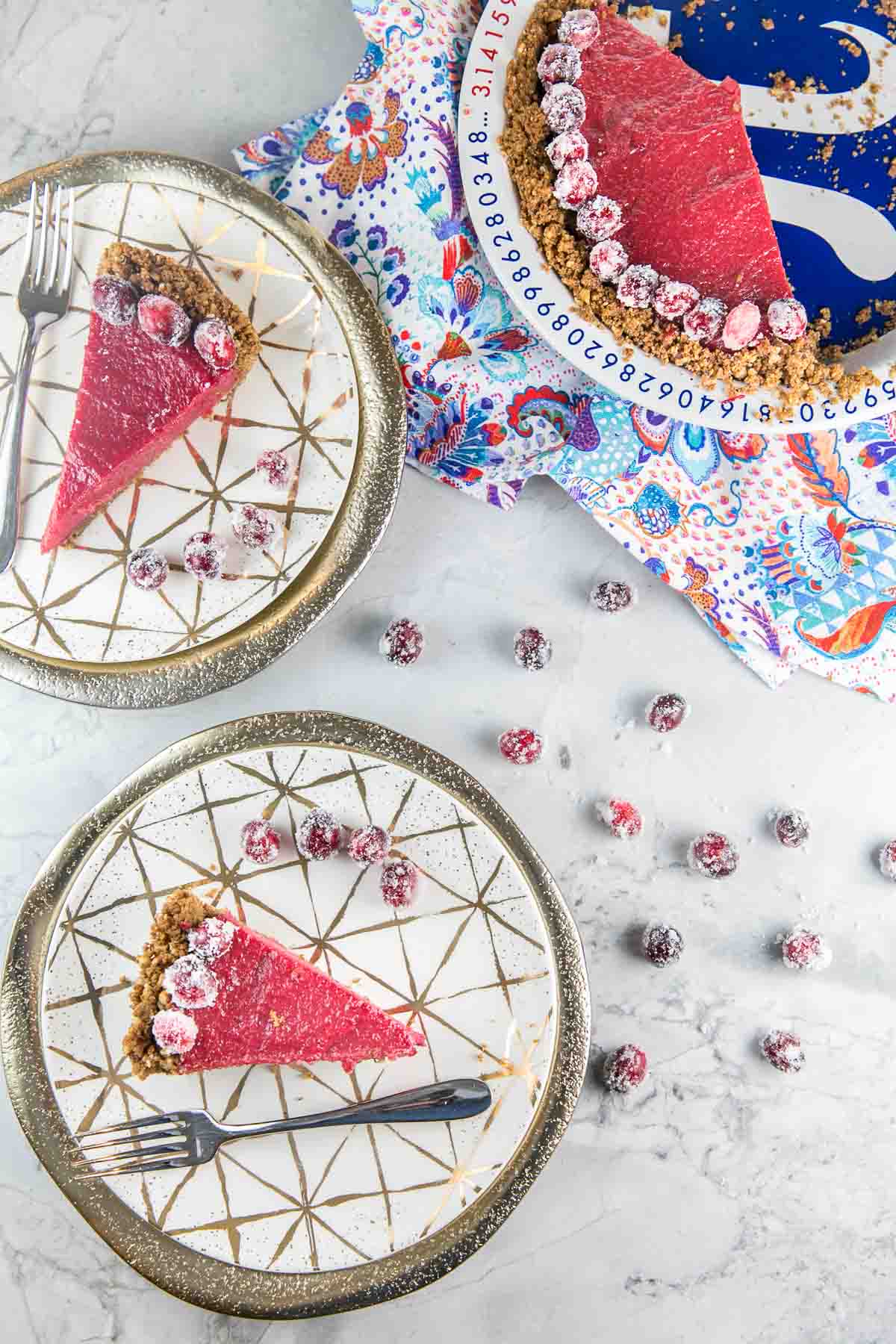 two slices of cranberry curd pie on decorative gold plates with gold chargers.