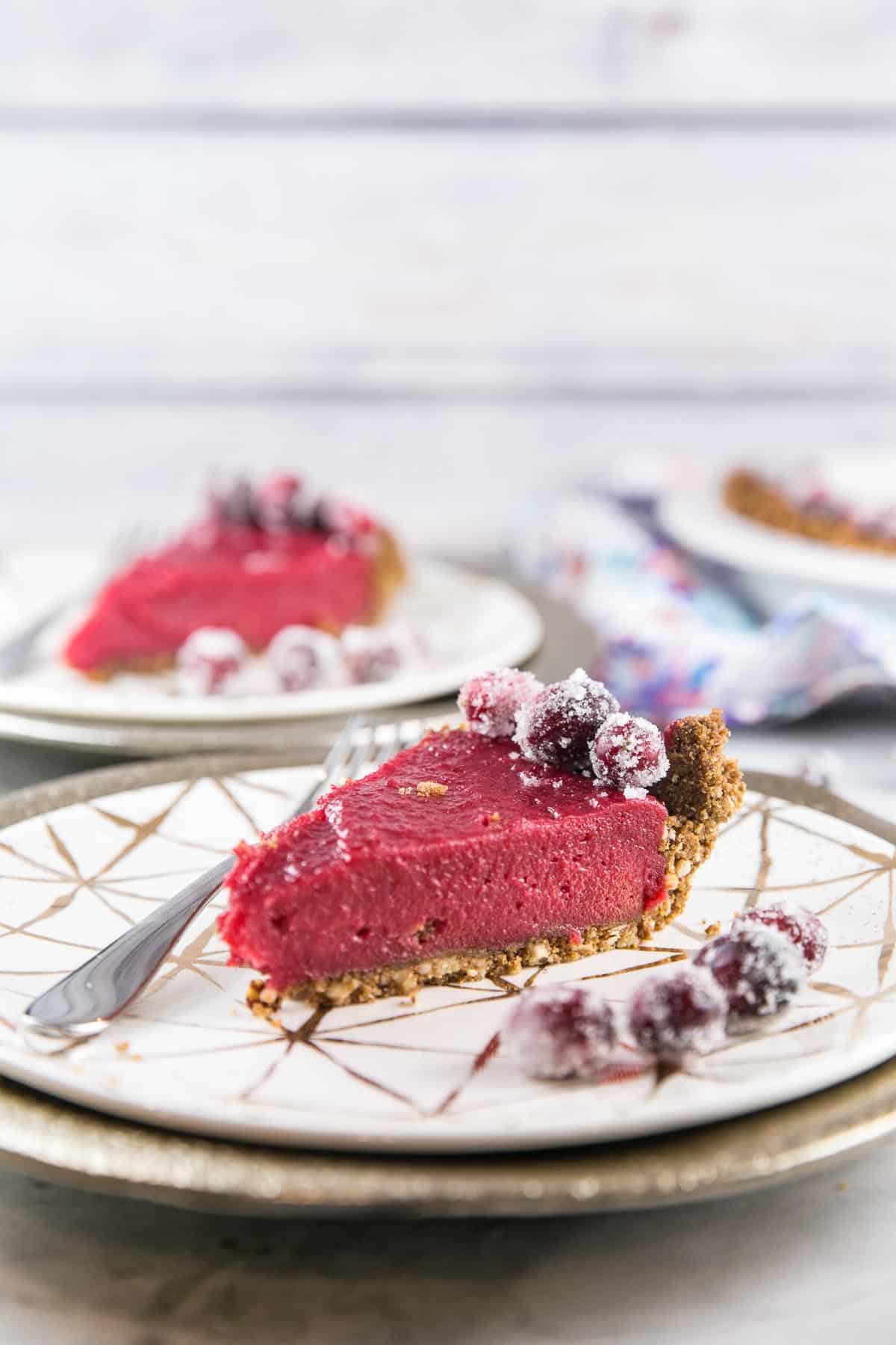 side view of two slices of cranberry curd pie with a gingersnap crust.