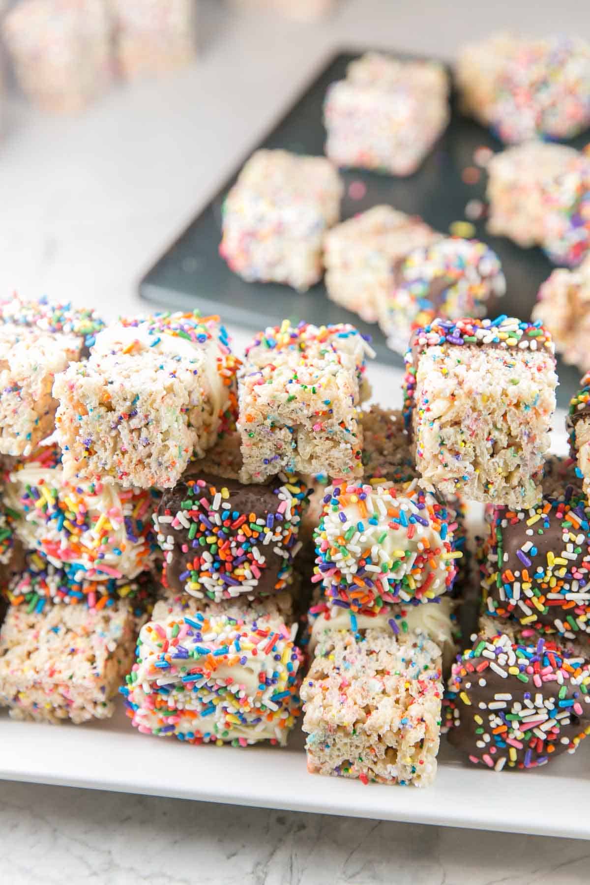 a stack of sprinkle rice krispie treats dipped in white chocolate