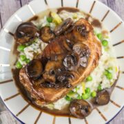 seared pork chop on a plate with mushrooms and risotto