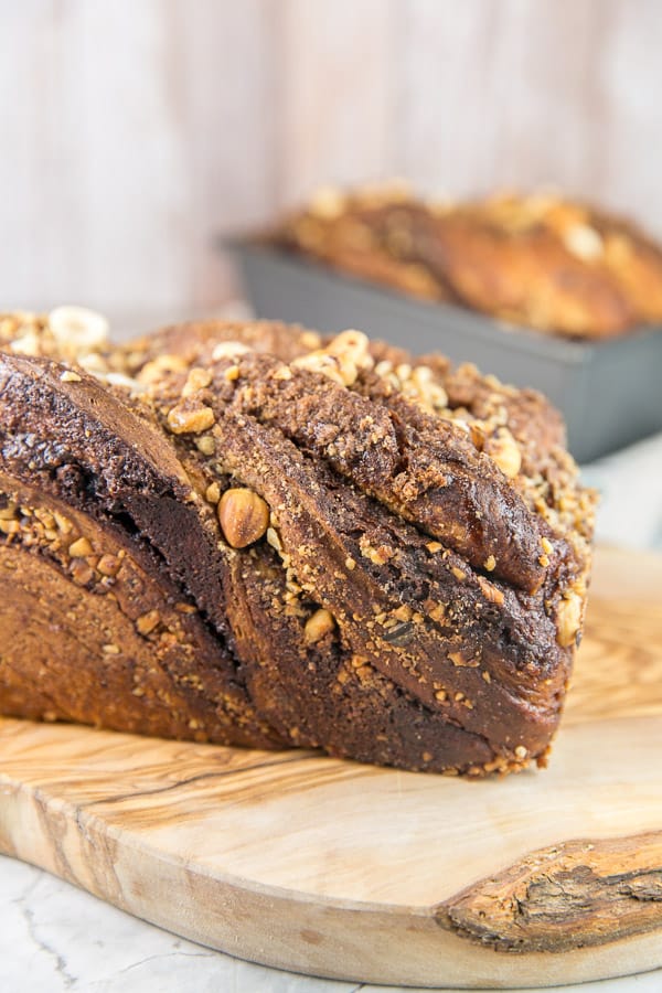 loaf of uncut cinnamon hazelnut babka on a wooden board.