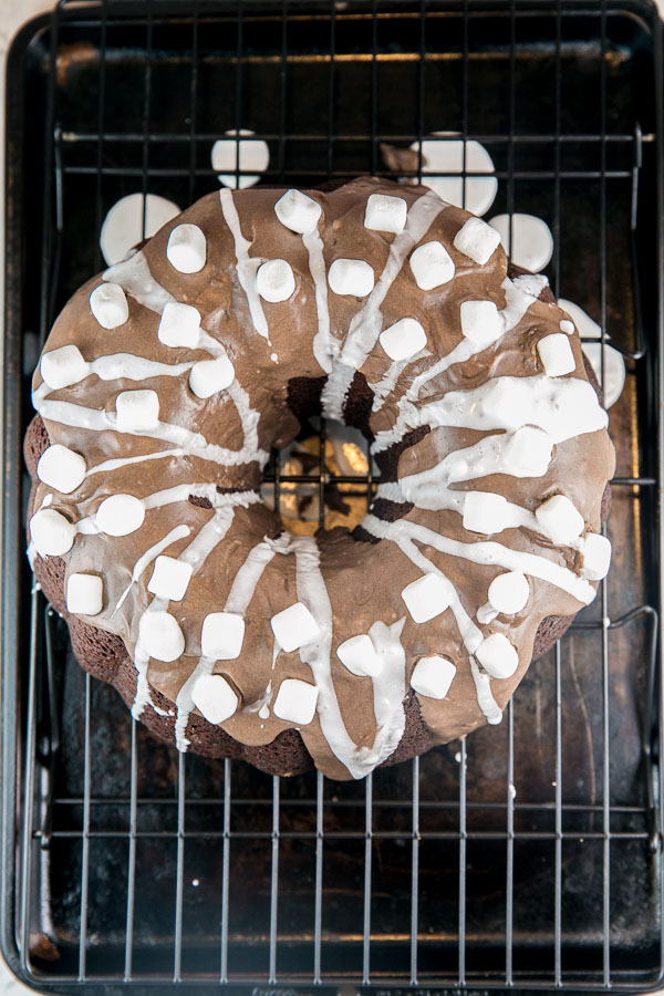 overhead photo of a chocolate bundt cake covered with hot chocolate glaze on a cooling rack.