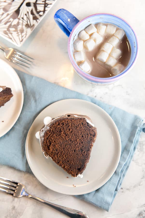 a slice of hot chocolate bundt cake on its side on a grey plate positioned on a blue dishtowel