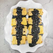 baked ricotta blintzes covered in a fresh blueberry sauce