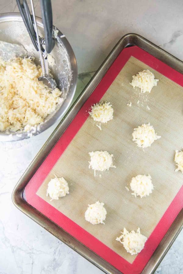 a baking sheet with scoops of unbaked coconut macaroons