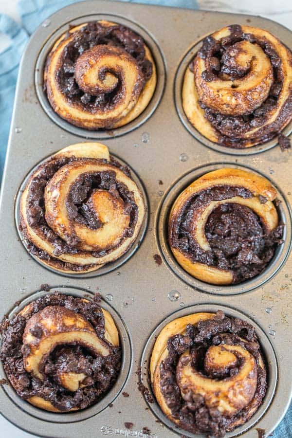 six chocolate swirled babka muffins in a muffin tin
