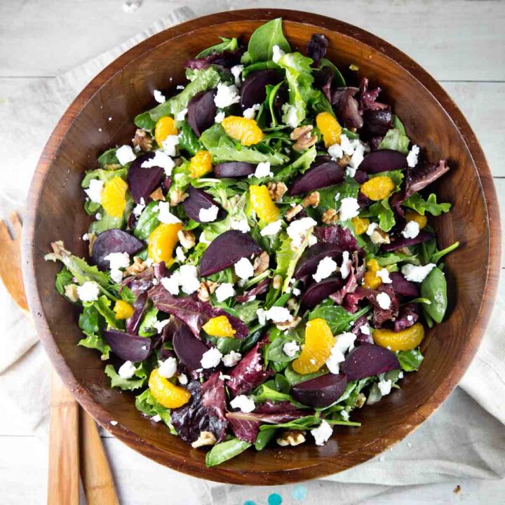 wooden salad bowl filled with mixed greens, roasted beets, and mandarin oranges