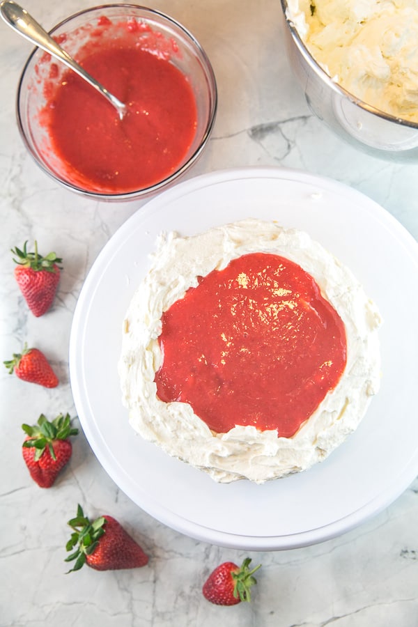 how to keep strawberry filling inside a layer cake by piping a thick layer of frosting around each layer of cake