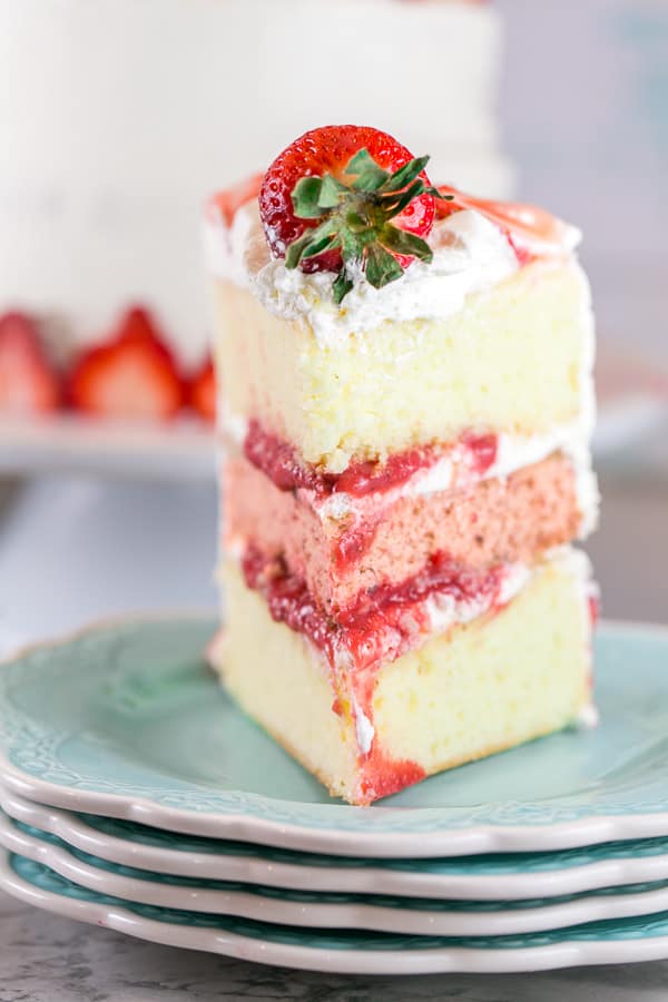 straight on view of a slice of strawberry layer cake showing the strawberry puree filling between each layer