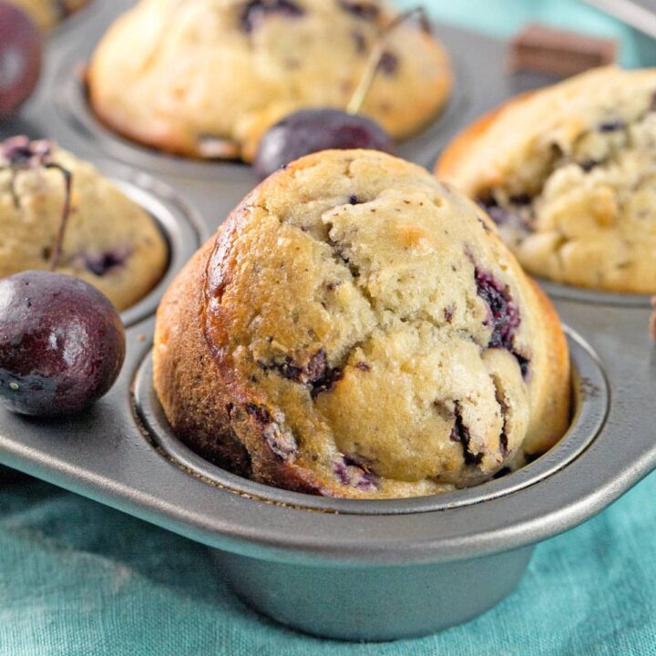 muffin tin filled with golden brown cherry chocolate chunk muffins
