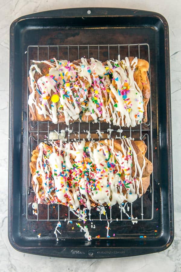 overhead view of two loaves of funfetti babka drizzled with glaze on a cooling rack