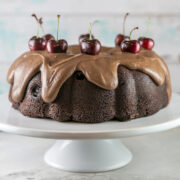 chocolate cherry bundt cake decorated with fudge frosting and fresh cherries