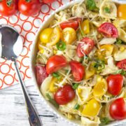 large white bowl filled with cheese tortellini and fresh tomatoes in a lemon balsamic dressing