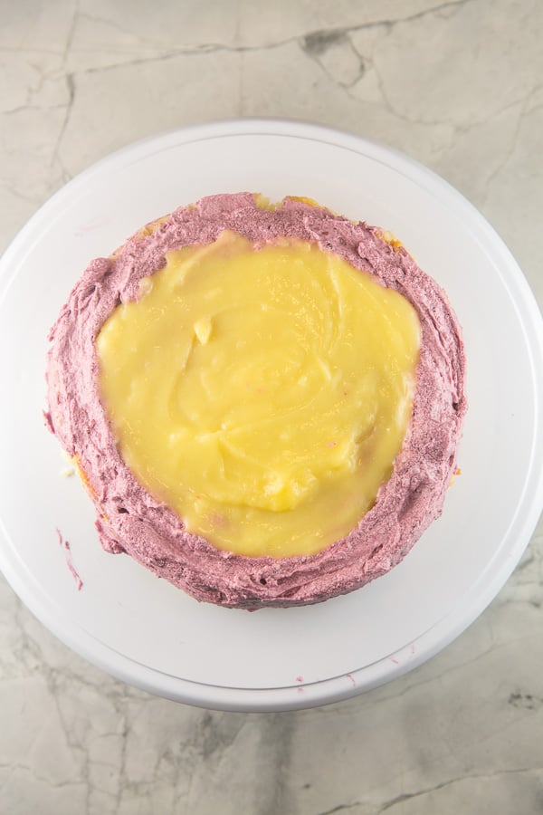 one layer of lemon curd cake covered with blackberry curd frosting filled in the middle with lemon curd