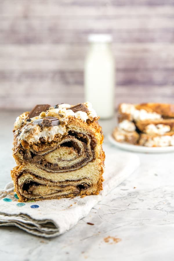 half a loaf of s'mores babka with slices of bread and a glass milk container in the background