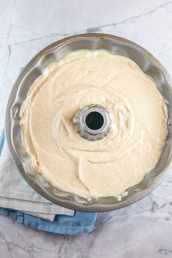 cream colored apple cider donut cake batter in a 12 bundt pan waiting to be baked